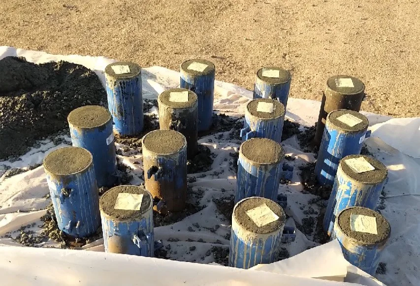 Freshly cast concrete test cylinders in blue moulds curing on a construction site